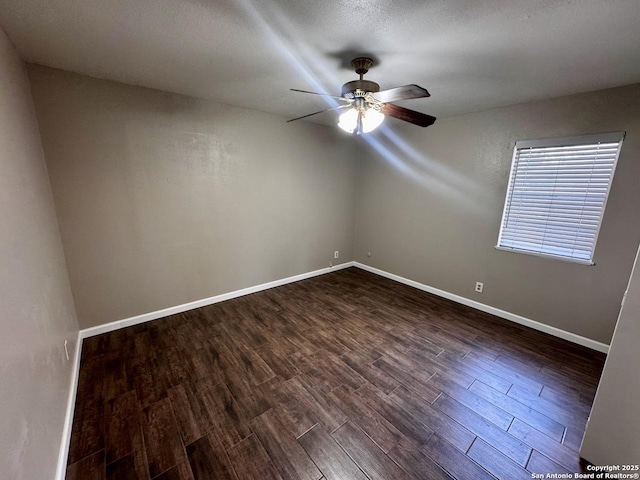 spare room with dark wood finished floors, baseboards, and a ceiling fan