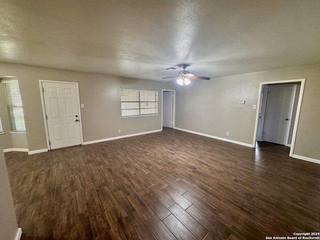 unfurnished living room featuring dark wood-style flooring, baseboards, a ceiling fan, and a textured ceiling