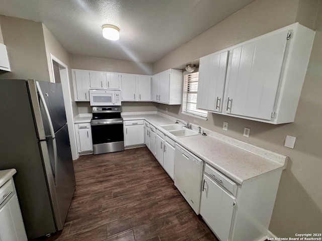 kitchen featuring white cabinets, a sink, light countertops, stainless steel appliances, and dark wood-type flooring