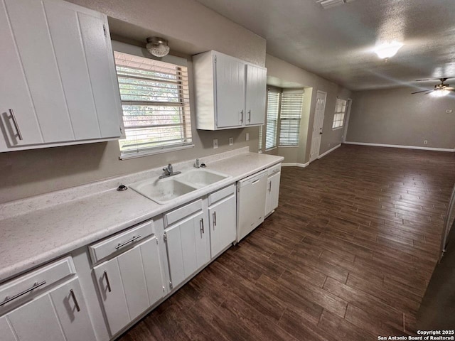 kitchen featuring ceiling fan, dishwasher, light countertops, a sink, and dark wood-style flooring