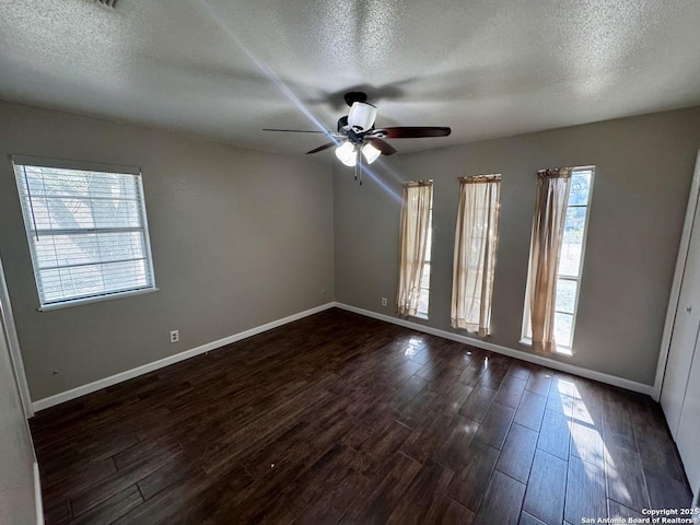 unfurnished room featuring dark wood finished floors, a textured ceiling, baseboards, and ceiling fan