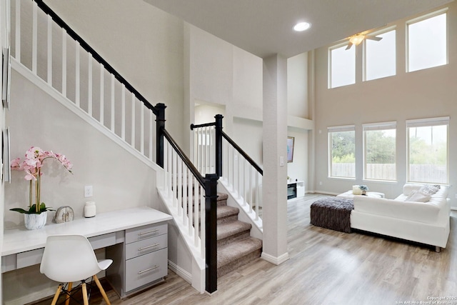 13324 Romulus Way, San Antonio, TX 78245 - stairway featuring wood finished floors, a towering ceiling, built in desk, baseboards, and recessed lighting