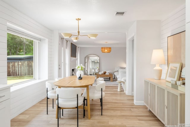 dining area with arched walkways, visible vents, an inviting chandelier, and light wood-style floors