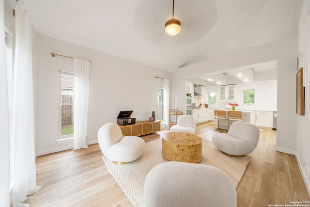 living room with light wood-style floors, lofted ceiling, and baseboards