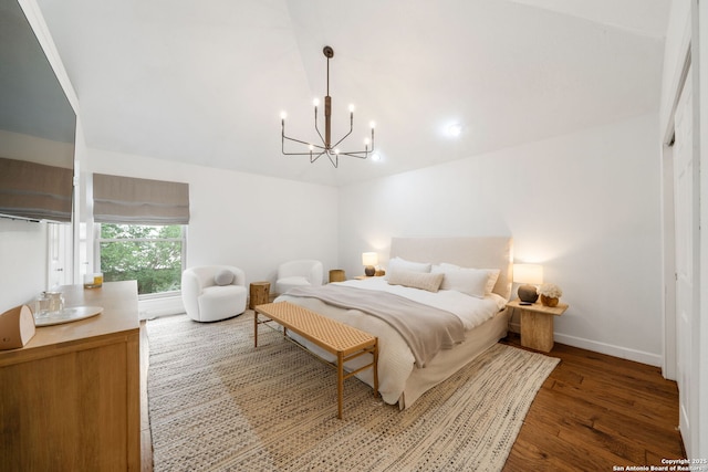 bedroom featuring baseboards, vaulted ceiling, wood finished floors, and an inviting chandelier