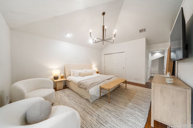 bedroom featuring vaulted ceiling, wood finished floors, a closet, a chandelier, and baseboards