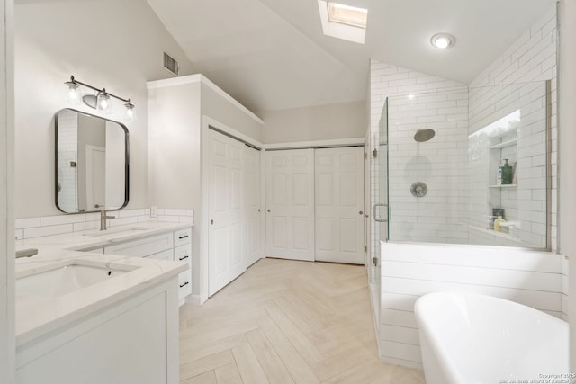 bathroom with lofted ceiling with skylight, a freestanding tub, a stall shower, and a sink