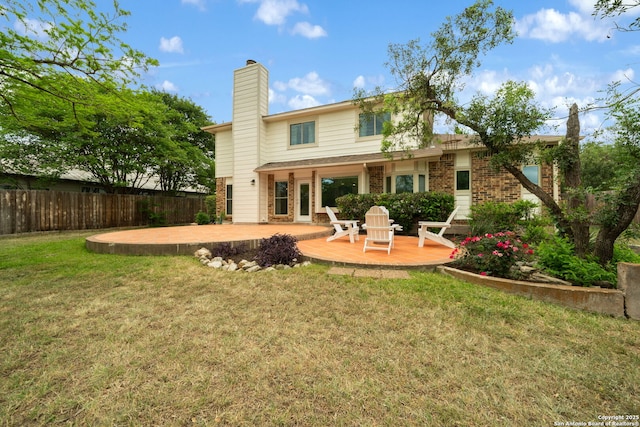 back of house featuring brick siding, a lawn, a patio, and fence