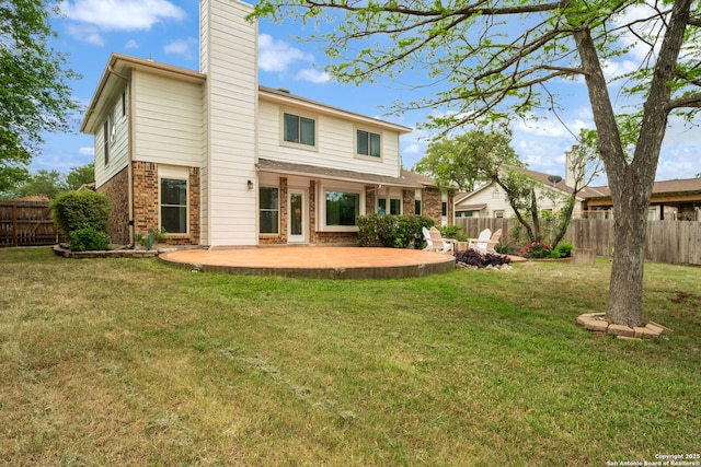 rear view of house featuring a fenced backyard, brick siding, a yard, and a patio