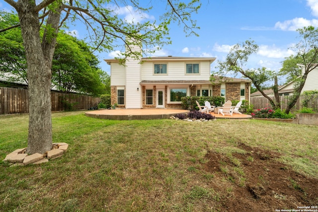 rear view of property with a fenced backyard, a chimney, a yard, and a patio