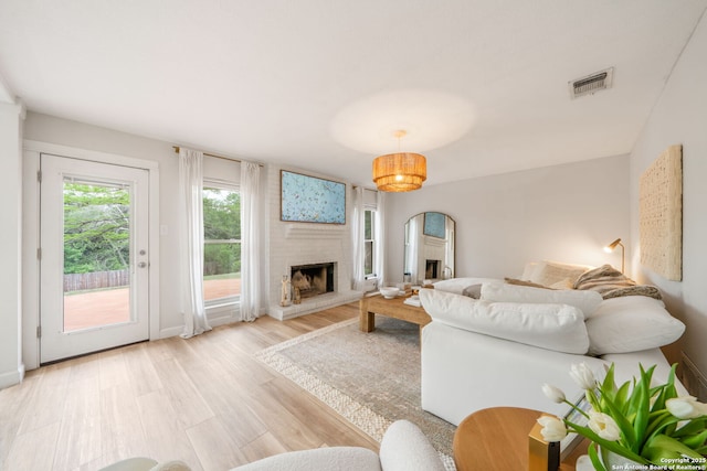 living room featuring light wood-style flooring, visible vents, and a fireplace
