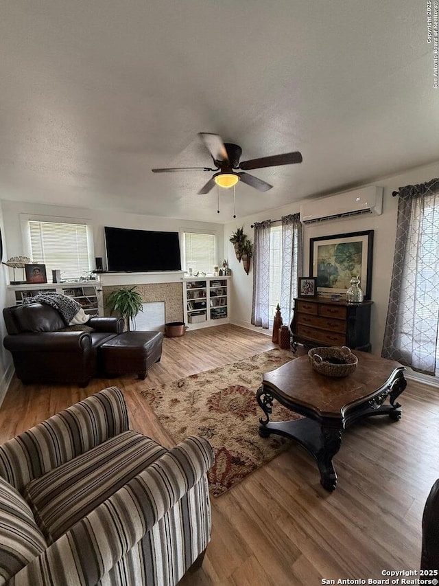 living room with ceiling fan, baseboards, wood finished floors, and a wall mounted air conditioner