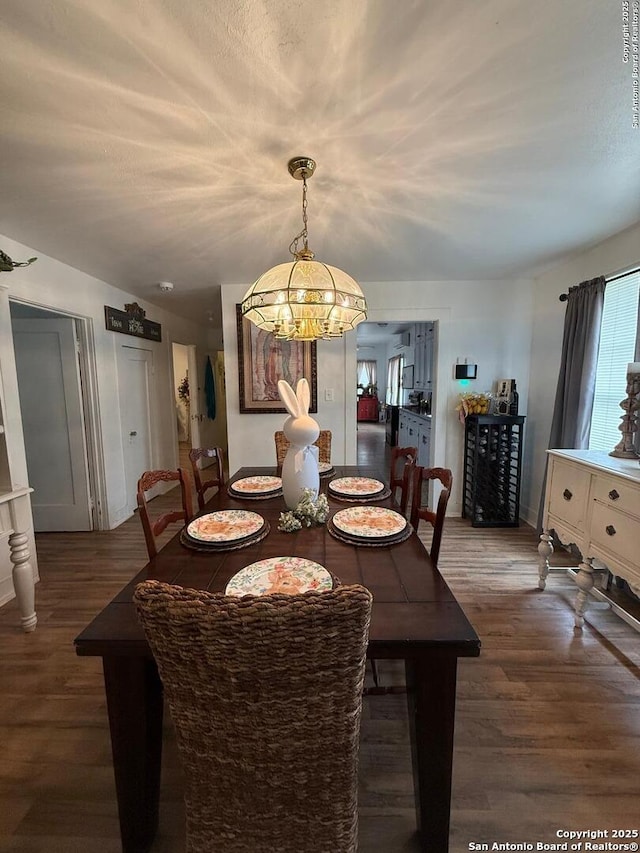 dining space with a notable chandelier, baseboards, and wood finished floors
