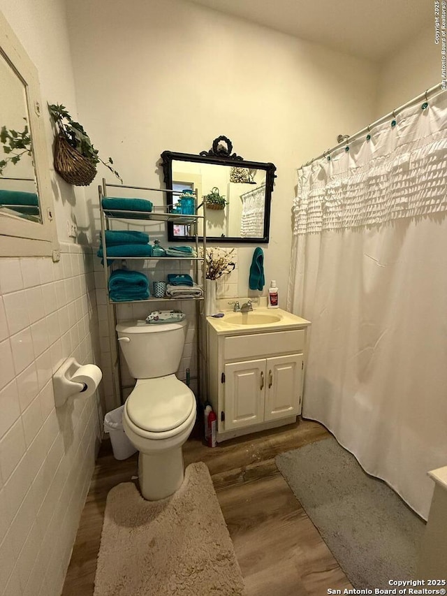 full bath featuring vanity, tile walls, toilet, and wood finished floors