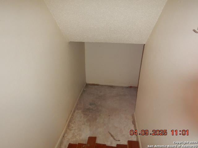 9704 Big Geronimo, San Antonio, TX 78254 - hallway with baseboards, carpet flooring, vaulted ceiling, and a textured ceiling