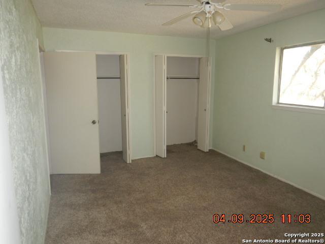 9704 Big Geronimo, San Antonio, TX 78254 - unfurnished bedroom with carpet flooring, two closets, and a ceiling fan