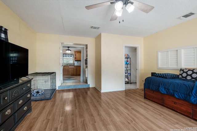 bedroom featuring a sink, light wood finished floors, baseboards, and visible vents