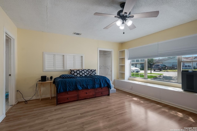 bedroom featuring visible vents, baseboards, wood finished floors, and a textured ceiling