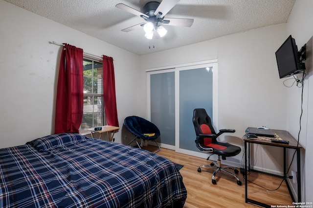 bedroom featuring a closet, light wood finished floors, a textured ceiling, and a ceiling fan