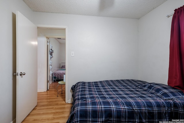 bedroom with light wood finished floors and a textured ceiling