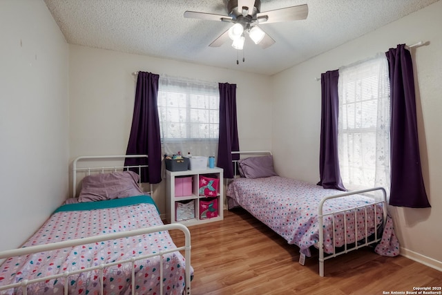 bedroom with light wood-style floors, ceiling fan, and a textured ceiling