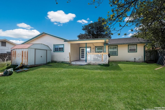 rear view of property featuring a shed, a yard, fence, and an outbuilding