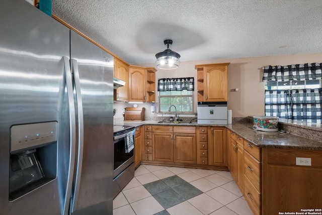 kitchen with dark stone countertops, a peninsula, open shelves, stainless steel appliances, and a sink