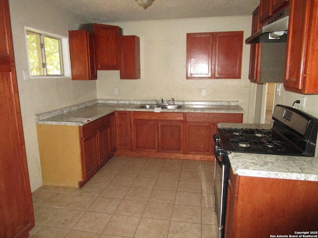 kitchen with a sink, stainless steel gas range oven, a textured ceiling, and under cabinet range hood