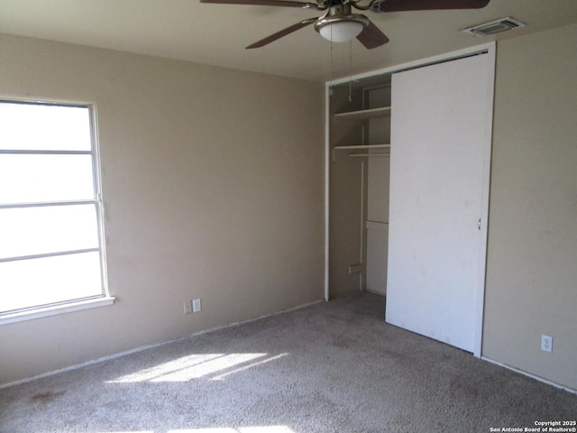 unfurnished bedroom featuring a closet, a ceiling fan, visible vents, and carpet floors