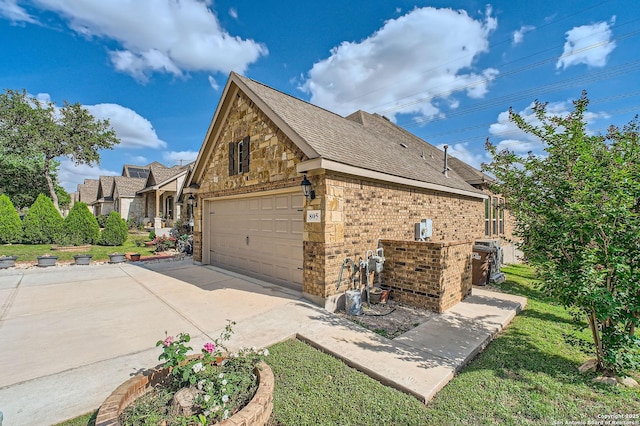 805 Raceland, San Antonio, TX 78245 - view of side of property featuring concrete driveway, stone siding, an attached garage, brick siding, and a shingled roof