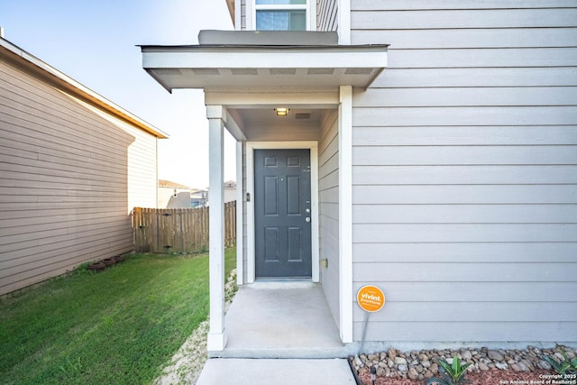 entrance to property with fence and a lawn