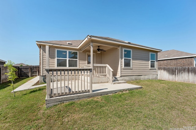 back of property with ceiling fan, a fenced backyard, and a lawn