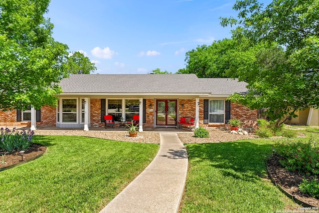 ranch-style home featuring brick siding, roof with shingles, a front lawn, and covered porch