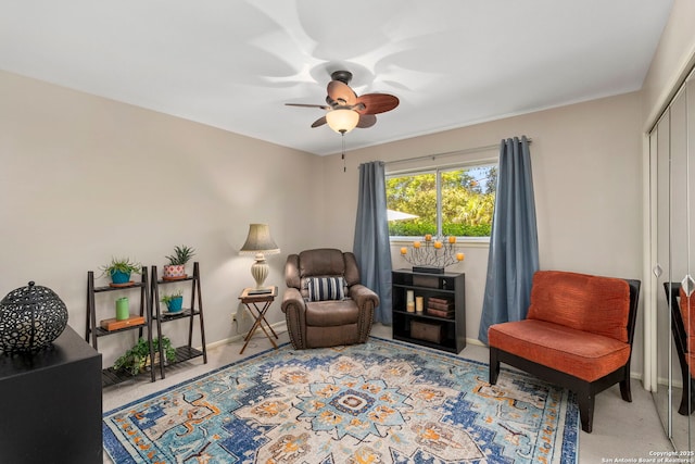 living area with carpet, a ceiling fan, and baseboards