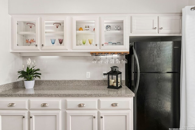 kitchen with light countertops, freestanding refrigerator, glass insert cabinets, and white cabinetry