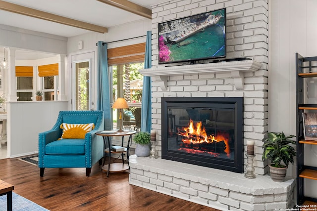 living area with beam ceiling, wood finished floors, and a fireplace