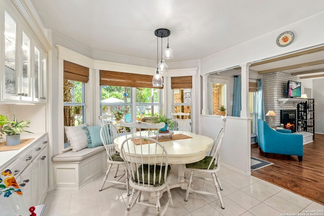 dining room featuring a brick fireplace and light tile patterned floors