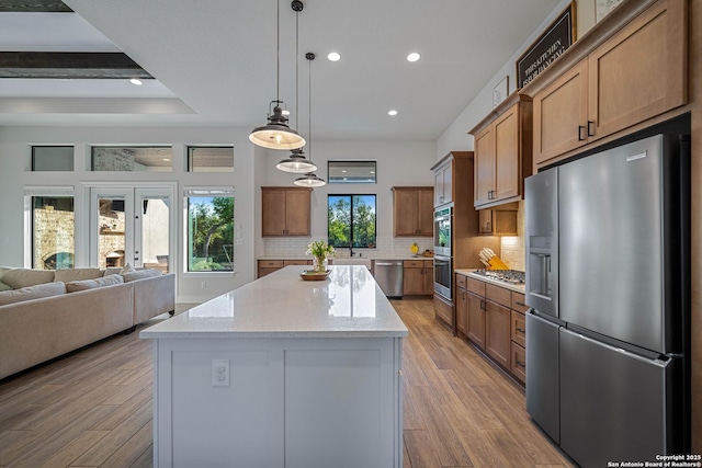 kitchen featuring light wood-style flooring, open floor plan, appliances with stainless steel finishes, and decorative backsplash