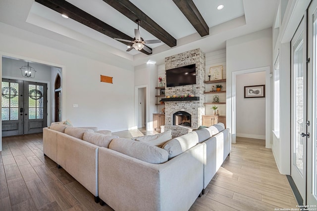 living room with a tray ceiling, baseboards, wood finished floors, and a fireplace