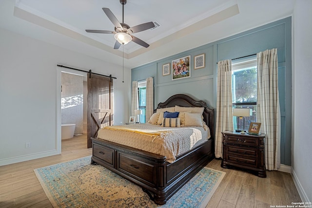 bedroom featuring a raised ceiling, light wood-style floors, crown molding, and multiple windows