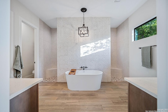 full bathroom featuring a freestanding tub, tile walls, a walk in shower, vanity, and wood finished floors