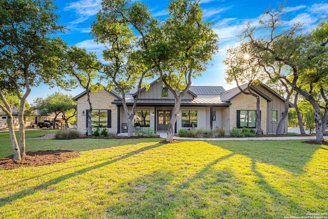 single story home featuring a front yard, stone siding, metal roof, and a standing seam roof