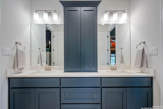 bathroom featuring double vanity, a sink, and a textured wall