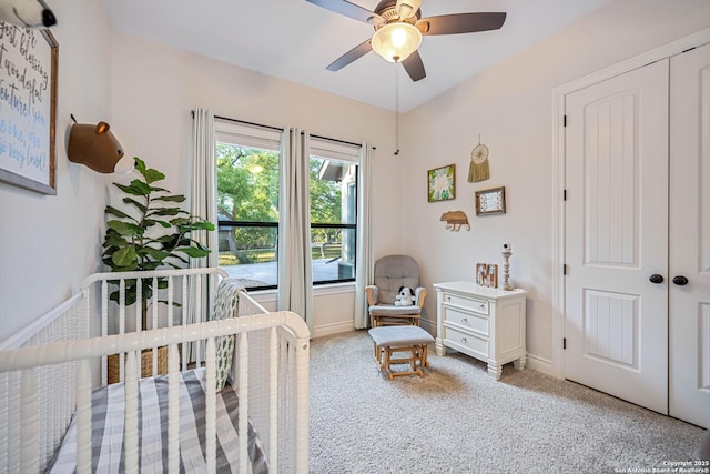 carpeted bedroom with a closet, baseboards, a ceiling fan, and a nursery area