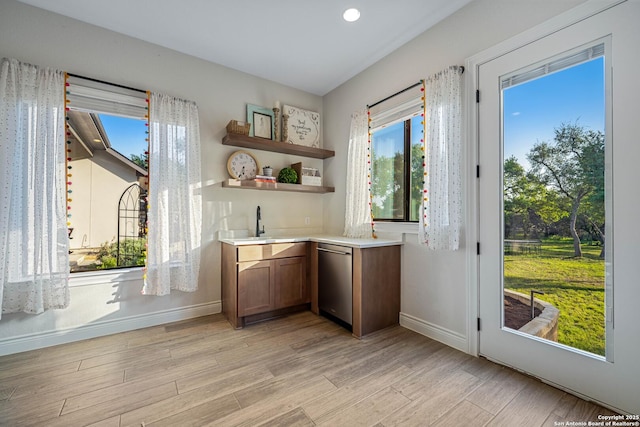 doorway with light wood-type flooring, wet bar, and baseboards