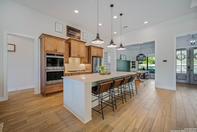 kitchen featuring visible vents, light countertops, a breakfast bar, stainless steel appliances, and light wood-style flooring