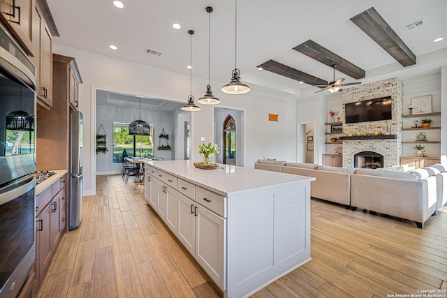kitchen with a ceiling fan, visible vents, light countertops, stainless steel appliances, and light wood finished floors