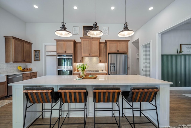 kitchen featuring tasteful backsplash, appliances with stainless steel finishes, light countertops, and a spacious island