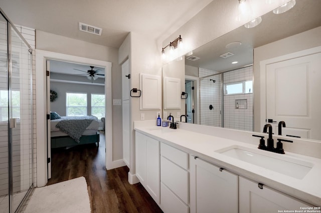 full bath featuring visible vents, a sink, a stall shower, and wood finished floors