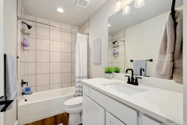 bathroom with vanity, visible vents, toilet, wood finished floors, and shower / tub combo